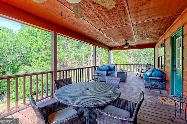 wooden deck featuring an outdoor hangout area, a ceiling fan, outdoor dining space, and a wooded view