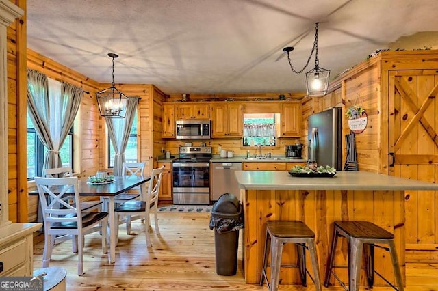 428 Gibbs Rd, Blairsville, GA 30512 - kitchen featuring stainless steel appliances, plenty of natural light, a chandelier, light wood finished floors, and wooden walls