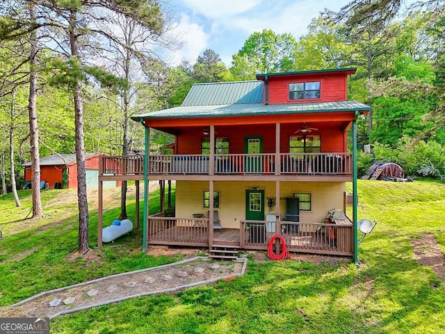 view of front of property with a ceiling fan, a deck, a front lawn, and metal roof