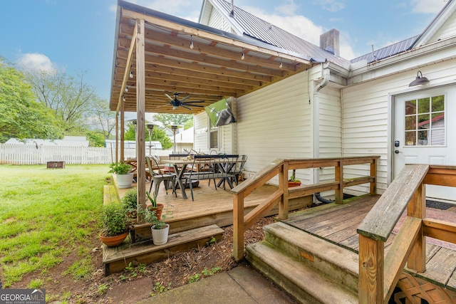 wooden deck featuring fence, outdoor dining space, ceiling fan, and a lawn