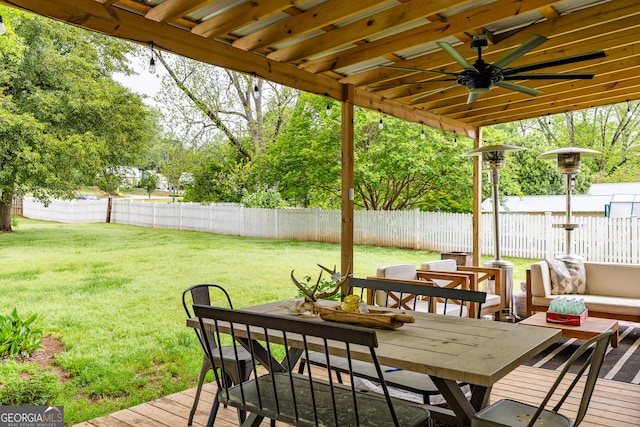 deck featuring a lawn, a ceiling fan, outdoor dining space, and a fenced backyard