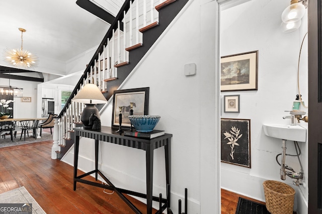 stairway with baseboards, hardwood / wood-style flooring, and a notable chandelier