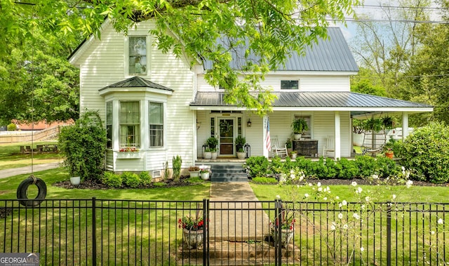 view of front facade with a front yard, a gate, metal roof, a porch, and a fenced front yard