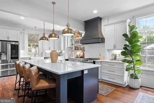 kitchen featuring a kitchen island, stainless steel appliances, custom exhaust hood, and backsplash