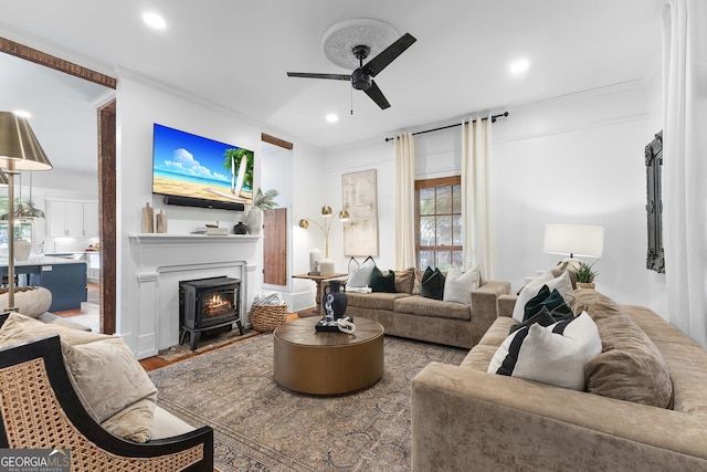 living area featuring a wood stove, a ceiling fan, recessed lighting, and wood finished floors