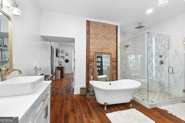 full bath with wood-type flooring, crown molding, a freestanding tub, vanity, and a shower stall