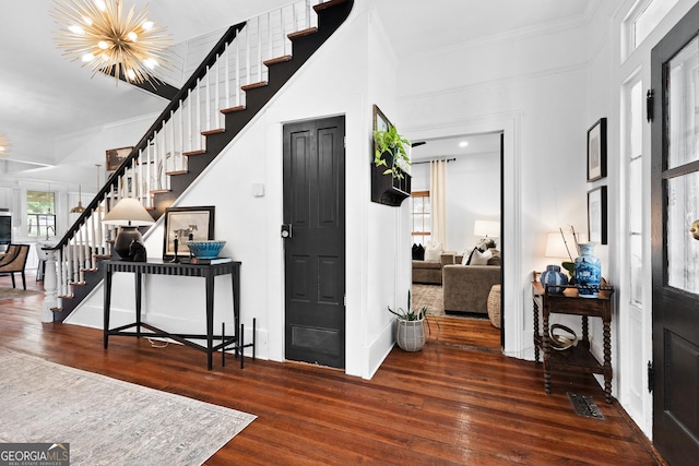 entrance foyer with crown molding, an inviting chandelier, stairs, baseboards, and hardwood / wood-style flooring