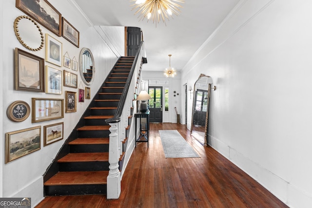 foyer entrance with an inviting chandelier, ornamental molding, stairway, and wood-type flooring