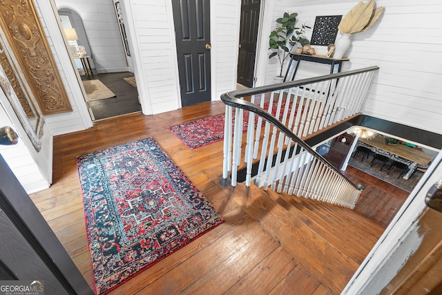 foyer entrance with wood-type flooring, arched walkways, and wooden walls