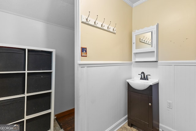 bathroom featuring vanity, ornamental molding, and a wainscoted wall