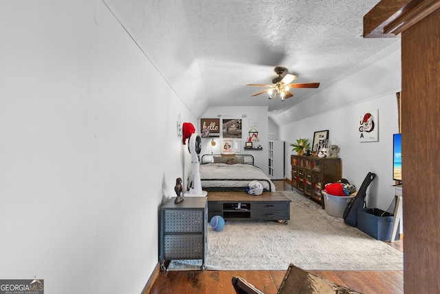 interior space featuring a ceiling fan, a textured ceiling, wood finished floors, and lofted ceiling