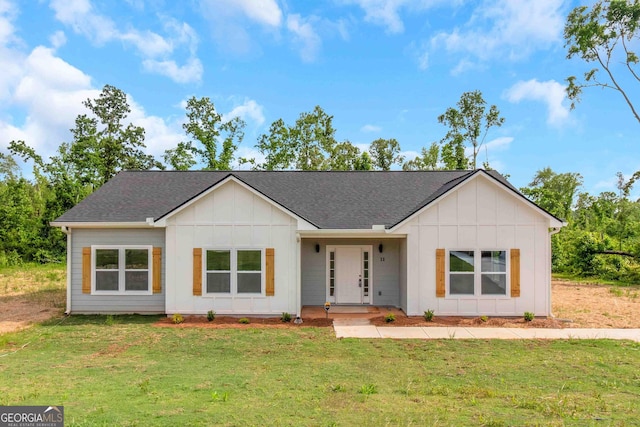 view of front of property with board and batten siding, roof with shingles, and a front lawn