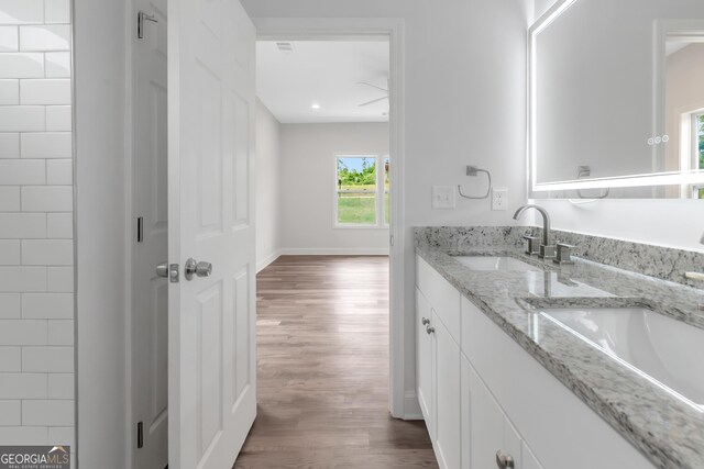 full bath featuring wood finished floors, double vanity, baseboards, and recessed lighting