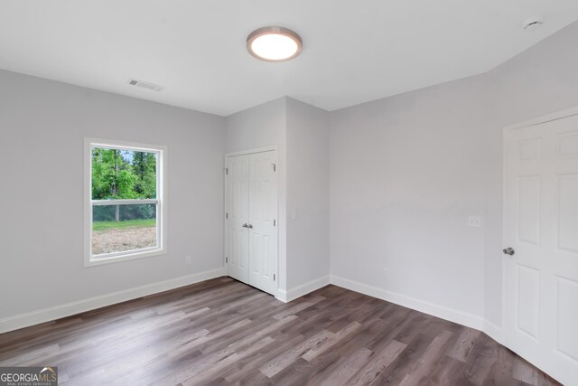 unfurnished bedroom with dark wood-style floors, baseboards, and a closet