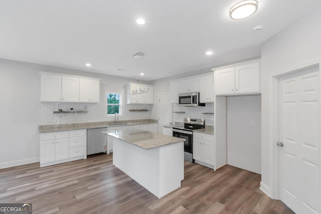 kitchen with stainless steel appliances, backsplash, white cabinetry, light wood-style floors, and recessed lighting
