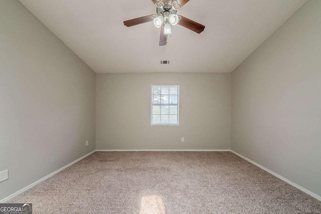 carpeted spare room with visible vents, baseboards, and ceiling fan