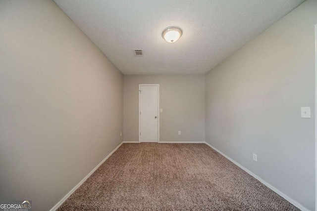 spare room featuring a textured ceiling, carpet, baseboards, and visible vents