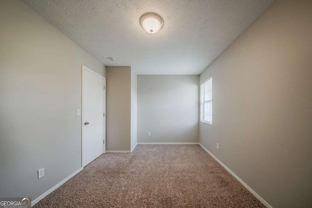 carpeted spare room with baseboards and a textured ceiling