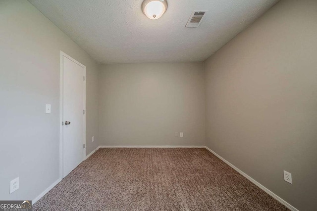 carpeted spare room featuring a textured ceiling, visible vents, and baseboards