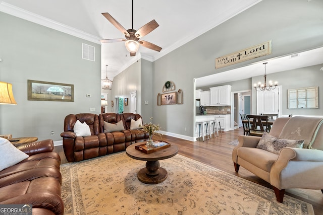 living room with a chandelier, dark wood-style floors, a towering ceiling, ornamental molding, and a ceiling fan