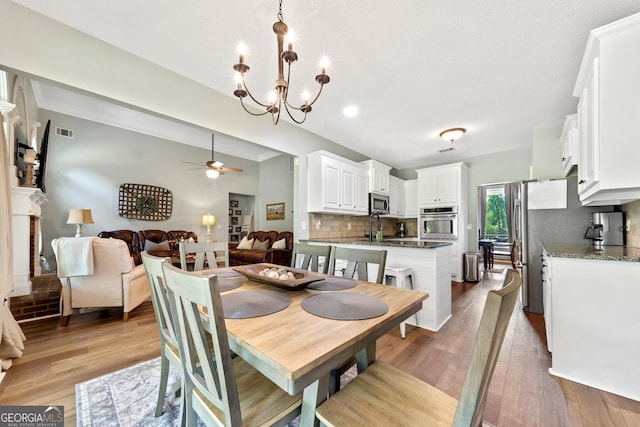 dining room with a ceiling fan, light wood finished floors, and a chandelier