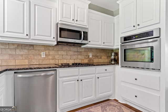 kitchen featuring appliances with stainless steel finishes, white cabinets, decorative backsplash, and a textured ceiling