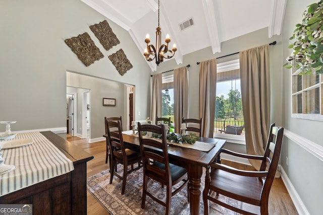 dining room with a chandelier, light wood-style flooring, high vaulted ceiling, beamed ceiling, and baseboards