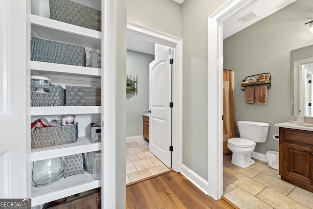 bathroom featuring vanity, toilet, and baseboards