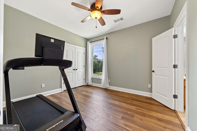 exercise room with wood finished floors, ceiling fan, and baseboards