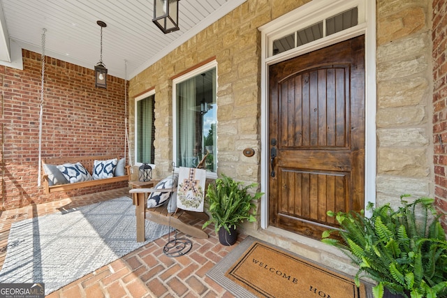 doorway to property featuring covered porch and stone siding