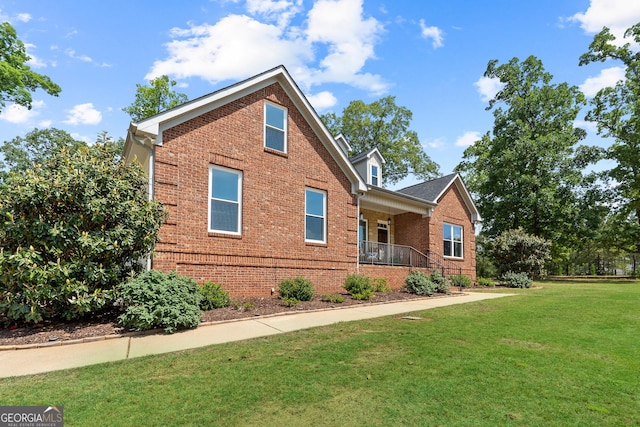 view of front of property with brick siding, a front yard, and a porch