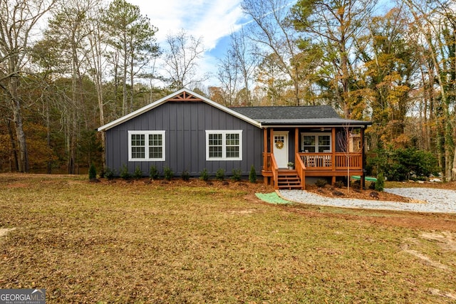 single story home with covered porch, board and batten siding, and a front yard