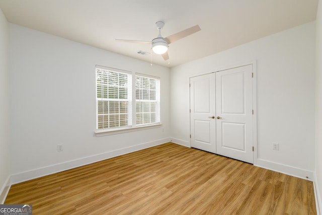 unfurnished bedroom featuring visible vents, a closet, baseboards, ceiling fan, and light wood-type flooring