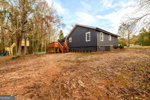 view of side of home with central air condition unit, stairs, board and batten siding, and a deck