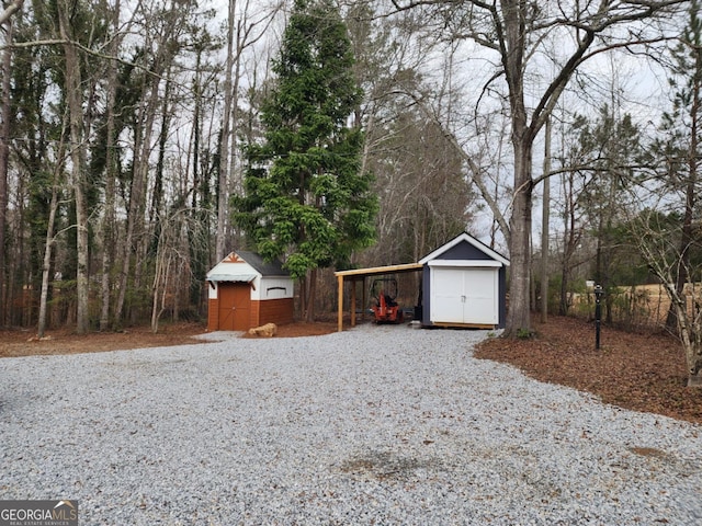 exterior space featuring an outdoor structure, a detached garage, a shed, and gravel driveway
