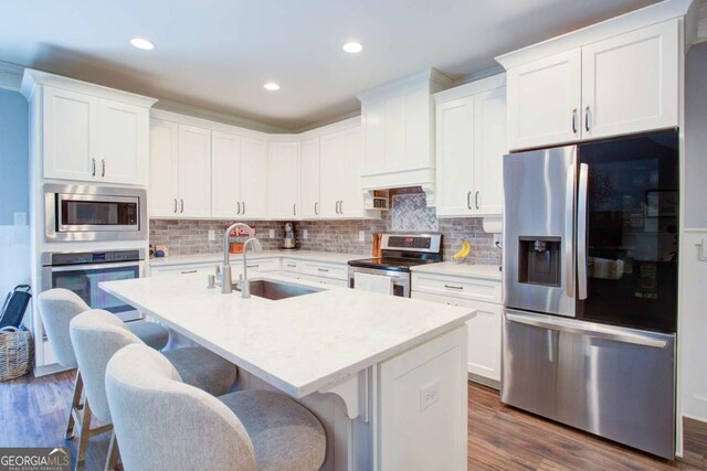 kitchen featuring a sink, appliances with stainless steel finishes, a breakfast bar, and dark wood-style flooring