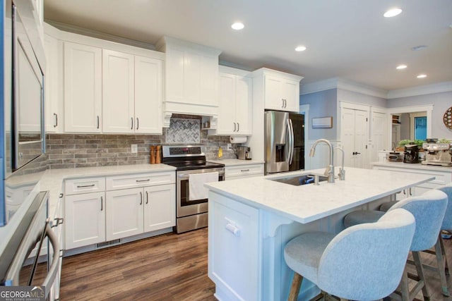 kitchen featuring decorative backsplash, a kitchen breakfast bar, appliances with stainless steel finishes, a sink, and ornamental molding