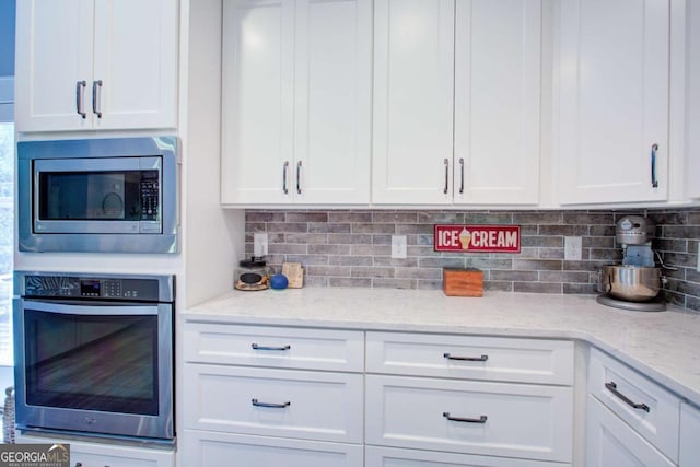 kitchen featuring backsplash, white cabinets, and stainless steel appliances