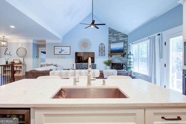 kitchen featuring open floor plan, a sink, wine cooler, and a wainscoted wall