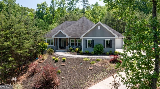 ranch-style home with a shingled roof, covered porch, and board and batten siding