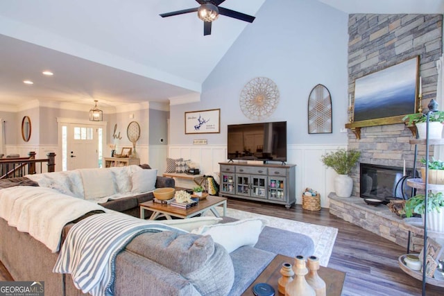 living area featuring a decorative wall, a ceiling fan, wood finished floors, and a wainscoted wall