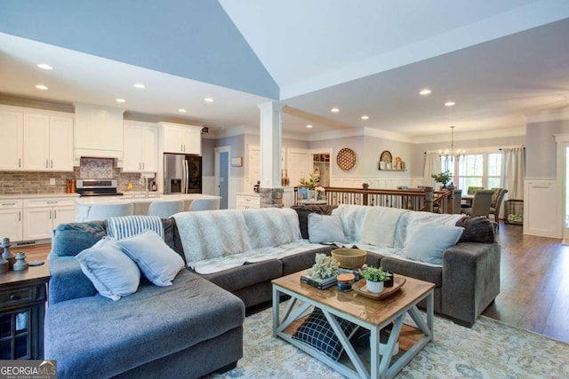 living room with light wood-style floors, a chandelier, recessed lighting, vaulted ceiling, and ornamental molding
