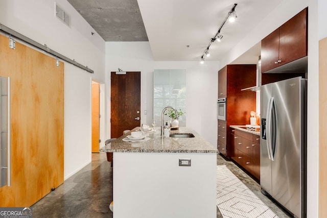 130 Arizona Ave NE Unit 104, Atlanta, GA 30307 - kitchen with stainless steel appliances, a sink, an island with sink, a barn door, and light stone countertops