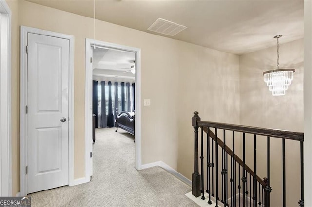 corridor with visible vents, an upstairs landing, carpet floors, baseboards, and a notable chandelier