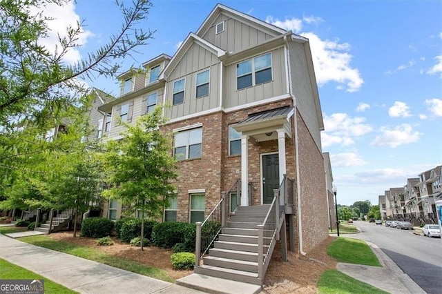 townhome / multi-family property featuring brick siding, a residential view, board and batten siding, and stairway
