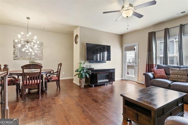 living area with baseboards, visible vents, wood finished floors, and ceiling fan with notable chandelier