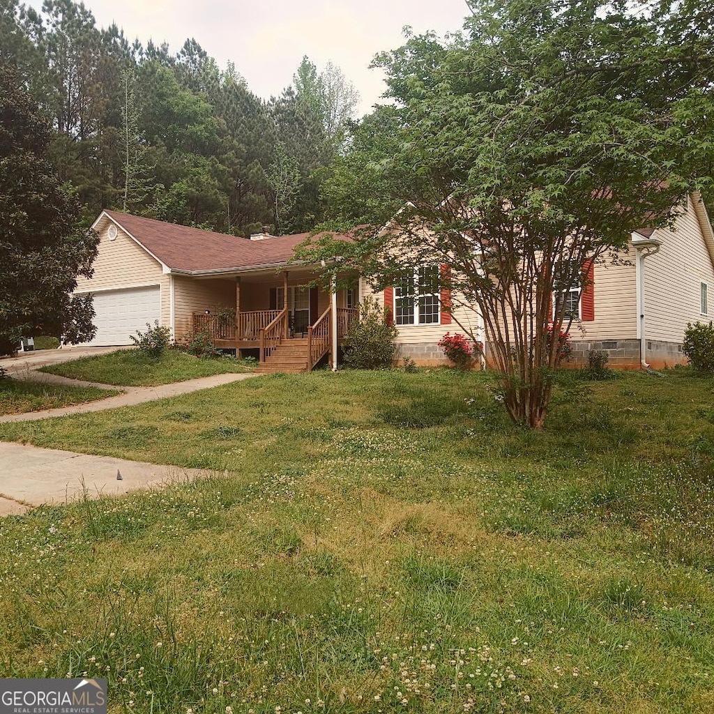 view of front of property with covered porch, an attached garage, concrete driveway, and a front lawn