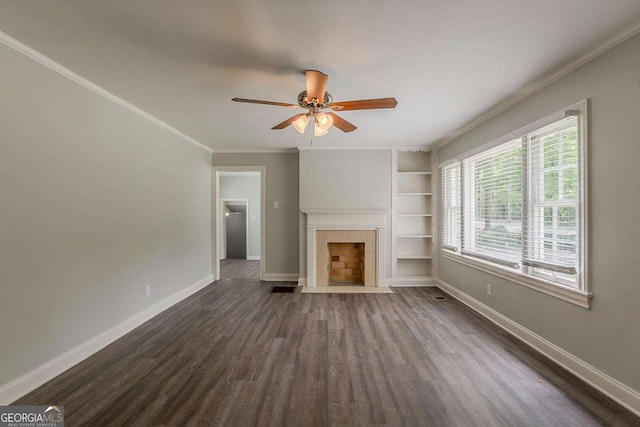 2465 Hogan Rd, Atlanta, GA 30344 - unfurnished living room with built in shelves, dark wood finished floors, crown molding, a ceiling fan, and a tiled fireplace
