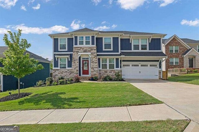 view of front of house featuring an attached garage, driveway, a front lawn, and stone siding