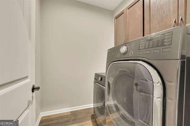 laundry area featuring baseboards, washing machine and dryer, cabinet space, and wood finished floors